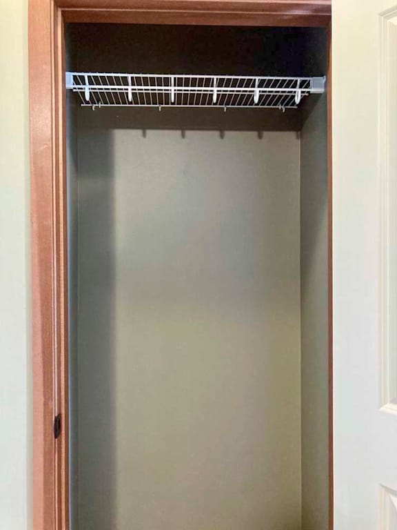 A coat closet with a wire shelf.