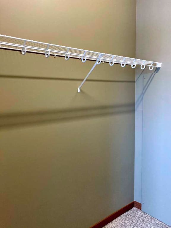 A walk-in closet with a wire shelf for hanging space.