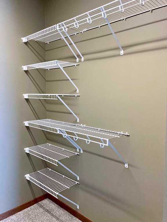 A walk-in closet with several wire shelves.