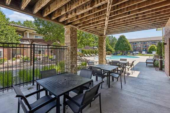 Covered patio amenity at Villas of Omaha at Butler Ridge with outdoor tables and chairs overlooking the community pool.
