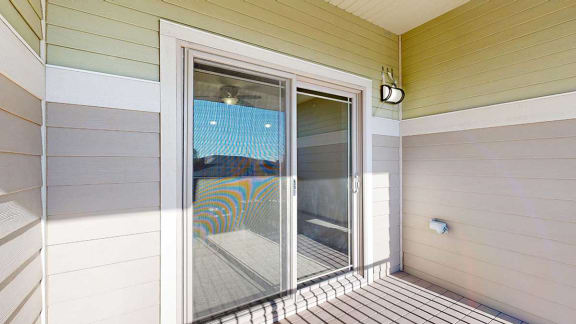 a balcony with a sliding glass door, exterior lighting, and electrical outlets