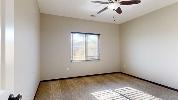 a bedroom with a large window and a ceiling fan