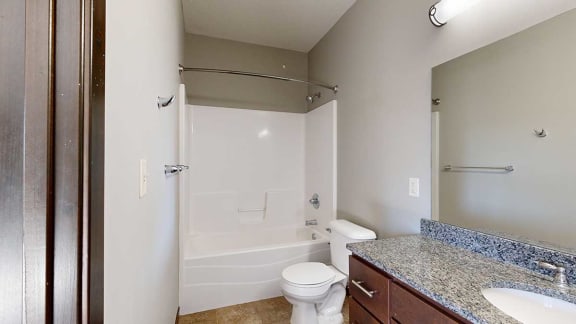 a bathroom with a shower and granite countertop vanity sink
