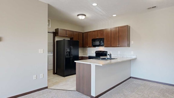a kitchen with granite countertops, black appliances, and bark brown cabinets