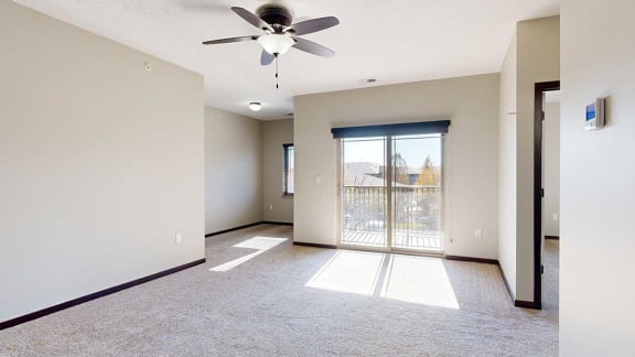 a living room with a sliding glass door to a balcony, a ceiling fan, and an attached den space
