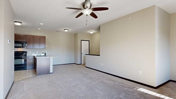 a living room with a ceiling fan next to a kitchen and dining room, with a coat closet