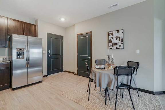 A kitchen with a table and chairs set up in front of it, next to the front entryway