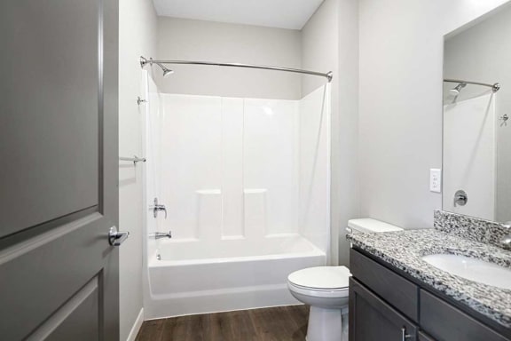 a bathroom with a sink with granite countertop and a tub shower