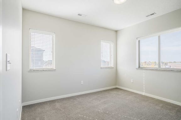 a bedroom with carpeting and several windows