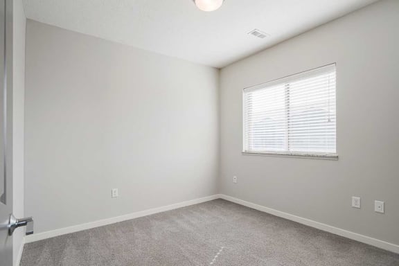 a bedroom with carpeting and a large window for natural light