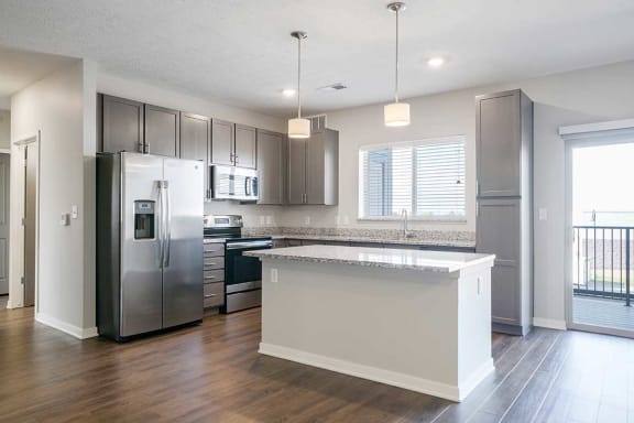 a kitchen with stainless steel appliances, grey cabinets, and a large island