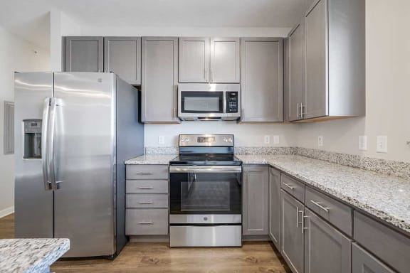 a kitchen with stainless steel appliances, grey cabinets, and granite counter tops