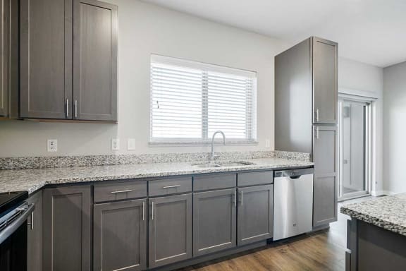 a kitchen with stainless steel appliances, grey cabinets, and granite counter tops