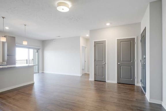 an open living room and dining room next to a hallway leading to the primary bedroom