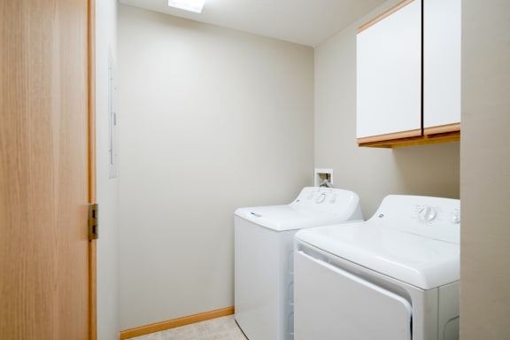 the laundry room has a washer and dryer and cabinet for storage