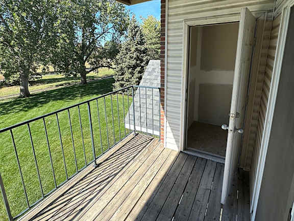 A deck with a railing and a door leading to a storage closet