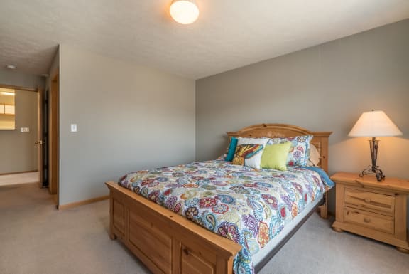 room with bed and one nightstand with lit lamp