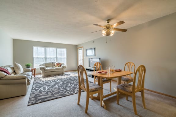 a living room with a dining room table and a ceiling fan
