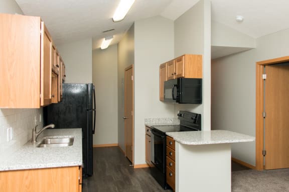 the view of a kitchen with a black refrigerator and a sink