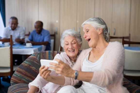 an older man and woman sitting on a couch looking at a laptop