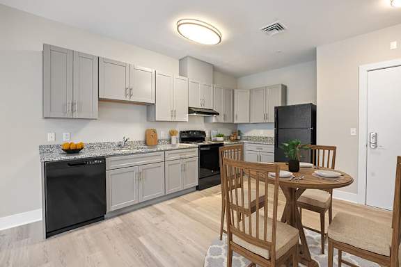 A kitchen with a table and chairs in front of it.