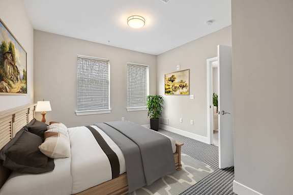 A bedroom with a bed, lamp, and painting on the wall.