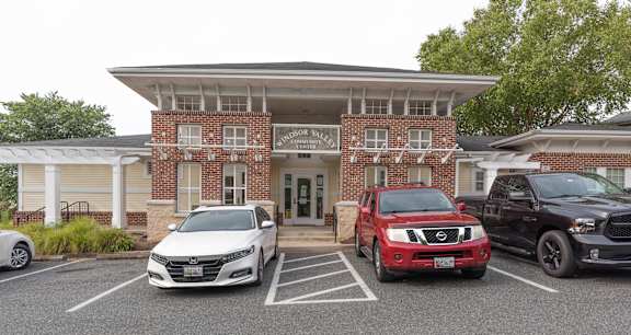 A white car is parked in front of a brick building.