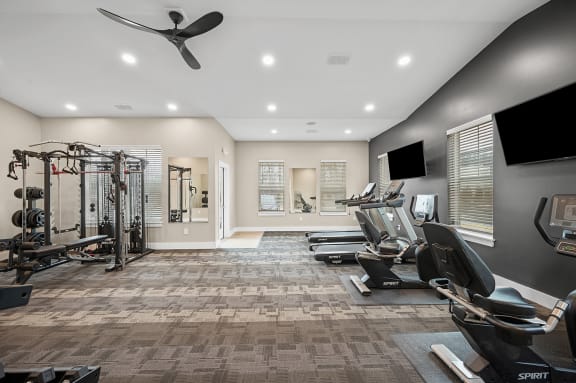 a gym with treadmills and a tv on the wall
