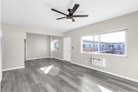 A spacious room with a ceiling fan and a large window.