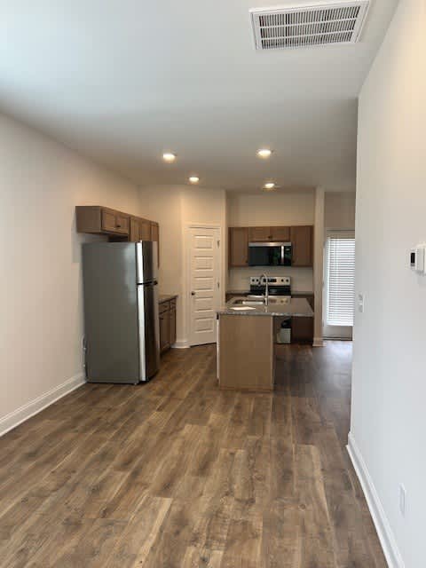 A kitchen with a refrigerator, microwave, and oven is shown.