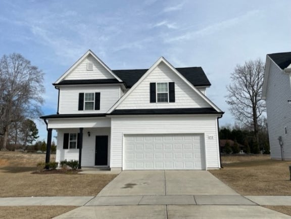 a white house with a garage door and a driveway