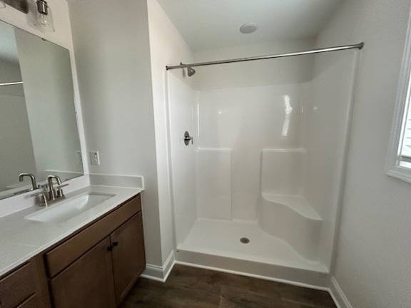 A white bathroom with a walk-in shower and a double sink vanity.