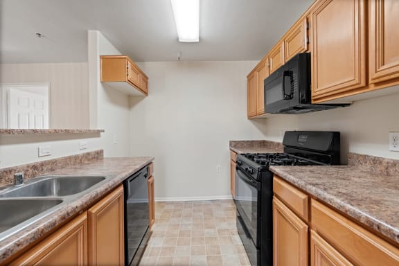 a kitchen with granite counter tops and a black stove and microwave  at Dronfield Astoria Apartments ,Sylmar, California