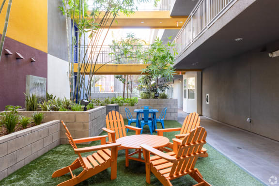 a courtyard with wooden chairs and tables and plants