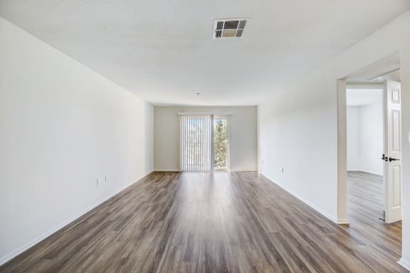 an empty living room with white walls and wood flooring
