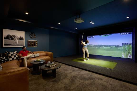 A man is sitting on a couch in front of a large screen playing a video game.