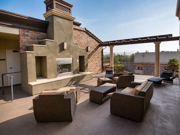 A patio with a fireplace and wicker furniture.