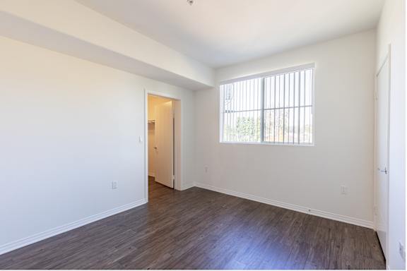 an empty bedroom with white walls and wood floors