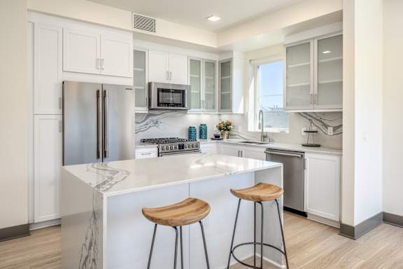 A kitchen with a marble island and stools.