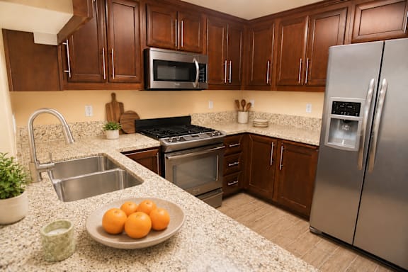A kitchen with brown cabinets and a stainless steel refrigerator.