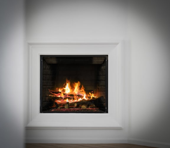 a fireplace with a roaring fire in a white room at Le Blanc Apartment Homes, Canoga Park, CA