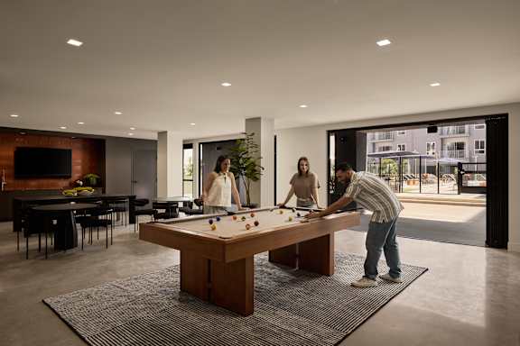 A man is playing pool in a room with a woman watching.