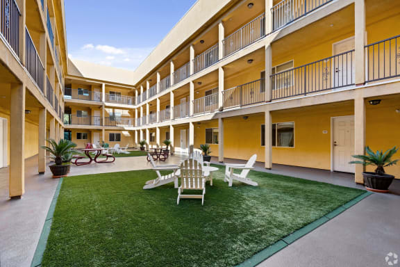 a courtyard with a lawn and chairs and tables at Dronfield Astoria Apartments, Sylmar