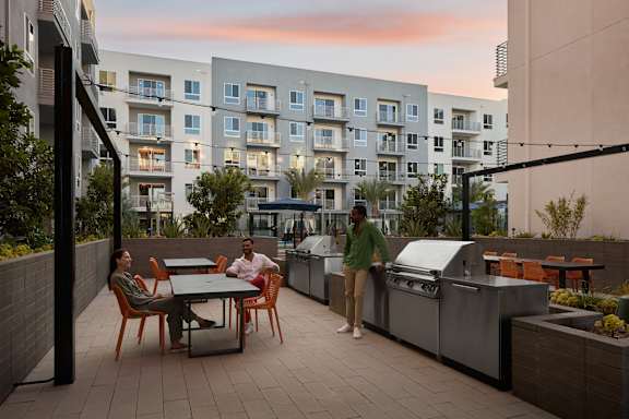 Two people are standing on a patio with a table and chairs.