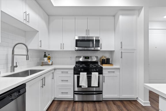 a white kitchen with stainless steel appliances and white cabinets