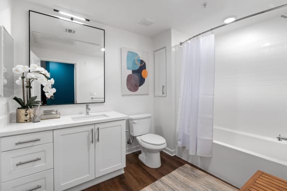 a bathroom with white cabinets and a white toilet and shower
