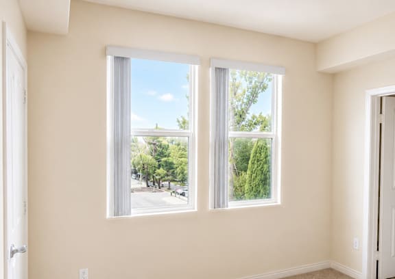 A room with two windows overlooking a street.