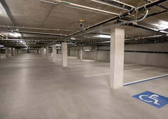 A parking garage with a blue and white handicap sign on the floor.