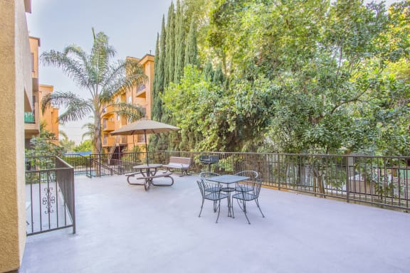 a patio with a table and chairs and trees in the background at Dronfield Astoria Apartments, Sylmar, California, 91342