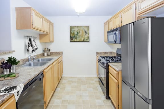 a kitchen with wooden cabinets and stainless steel appliances at Dronfield Astoria Apartments, California,  91342